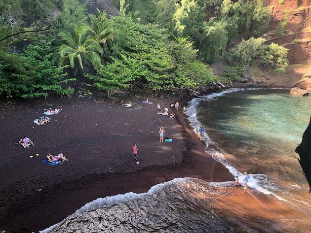 Red Sand Beach - Road to Hana - Maui. Small red beach with a little bit of ocean. Surrounded by green trees and bushes. 