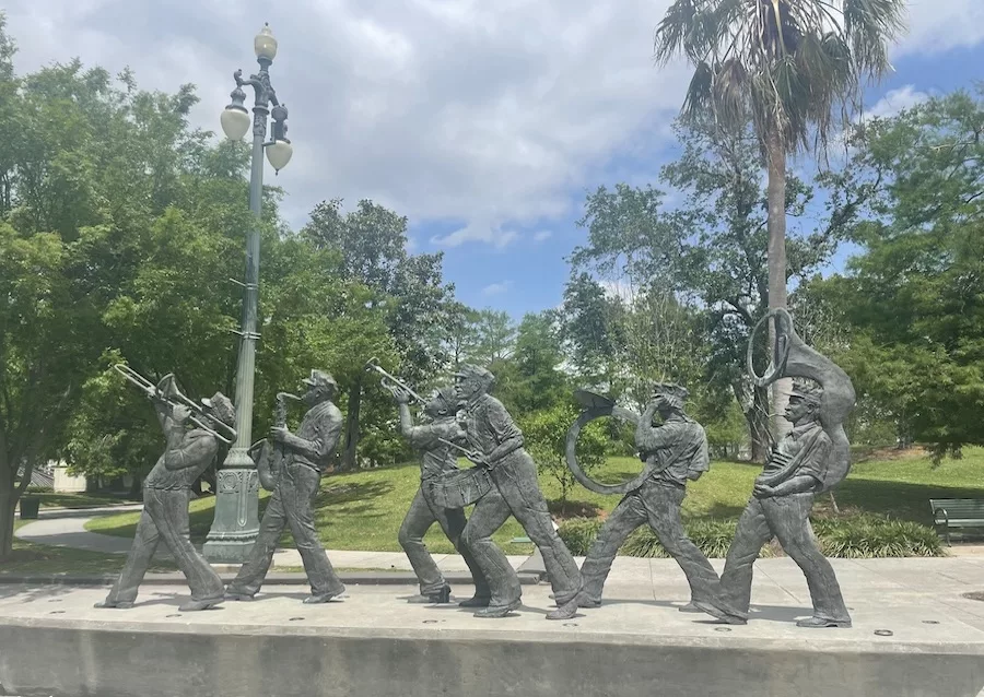 Image of metal musician sculptures in Louis Armstrong Park surrounded by green foliage - Honest Review of New Orleans