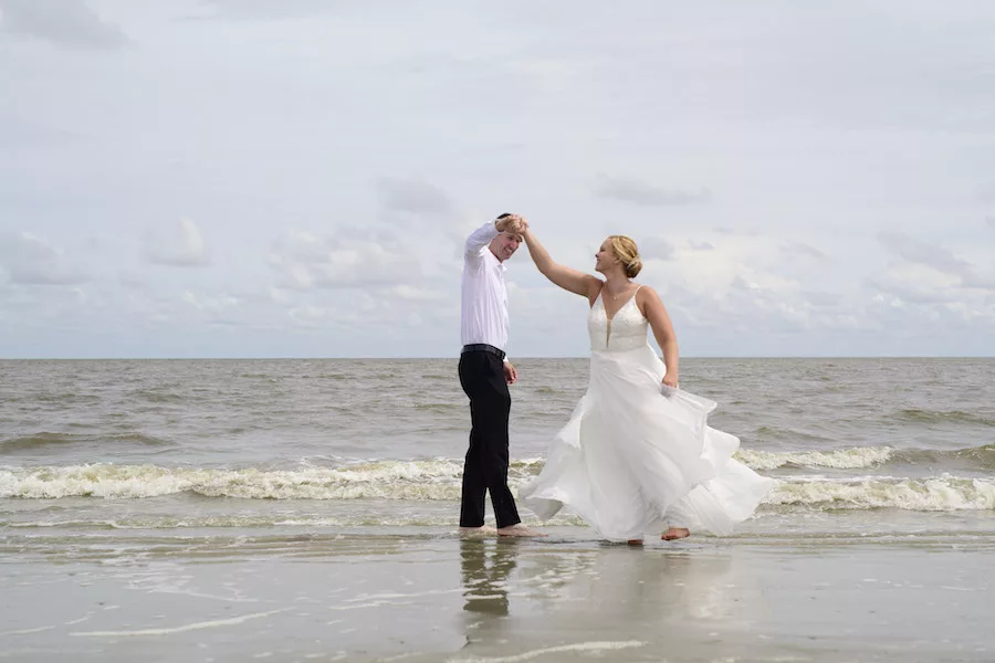 Husband and Wife dancing on beach in wedding attire. 
