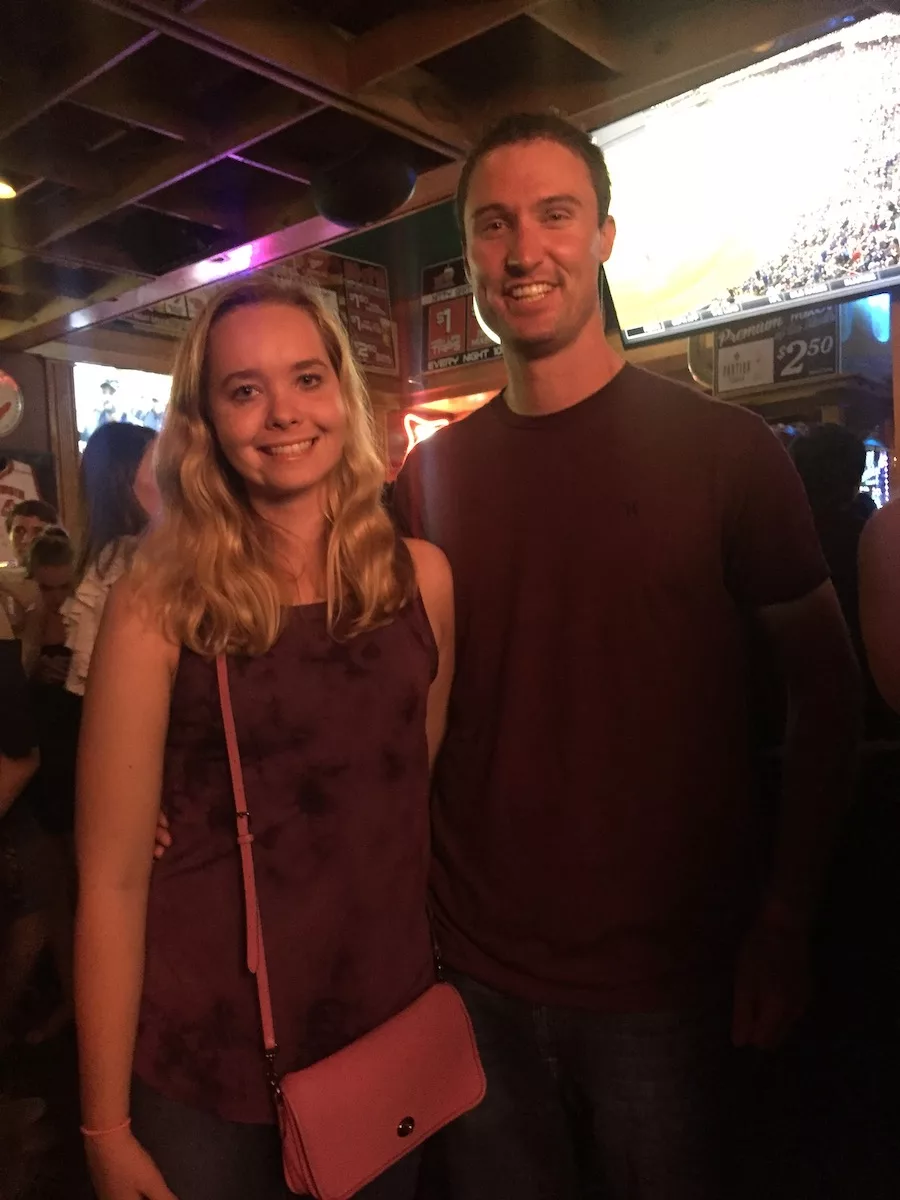 Couple posing for a photo in a crowded bar. 