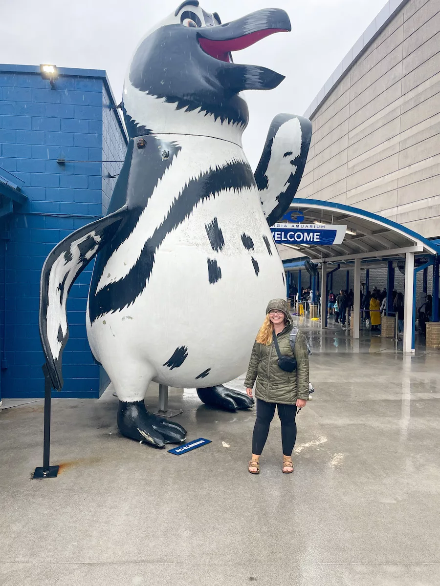 Georgia Aquarium - Young woman standing in front of giant penguin statue 