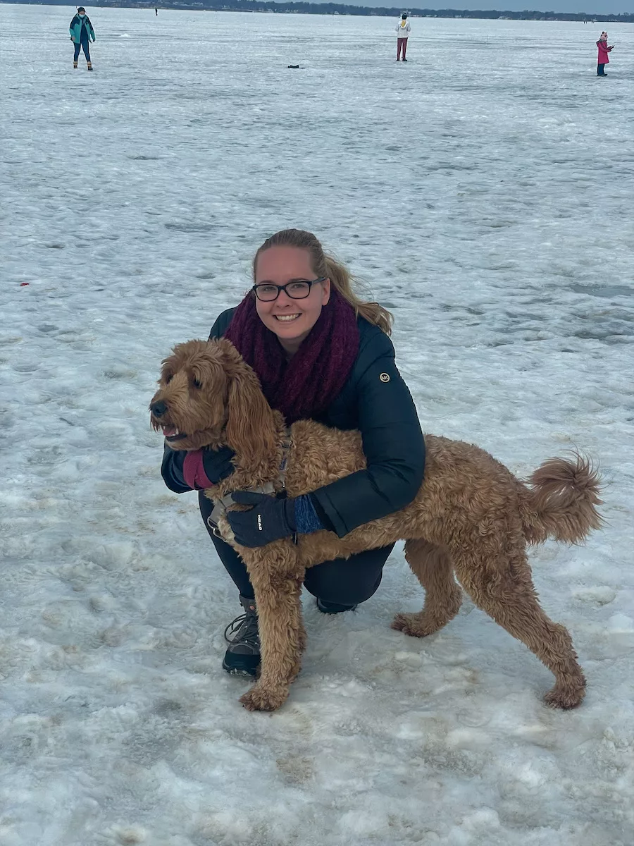 Young women and her medium-sized dog on the ice. 