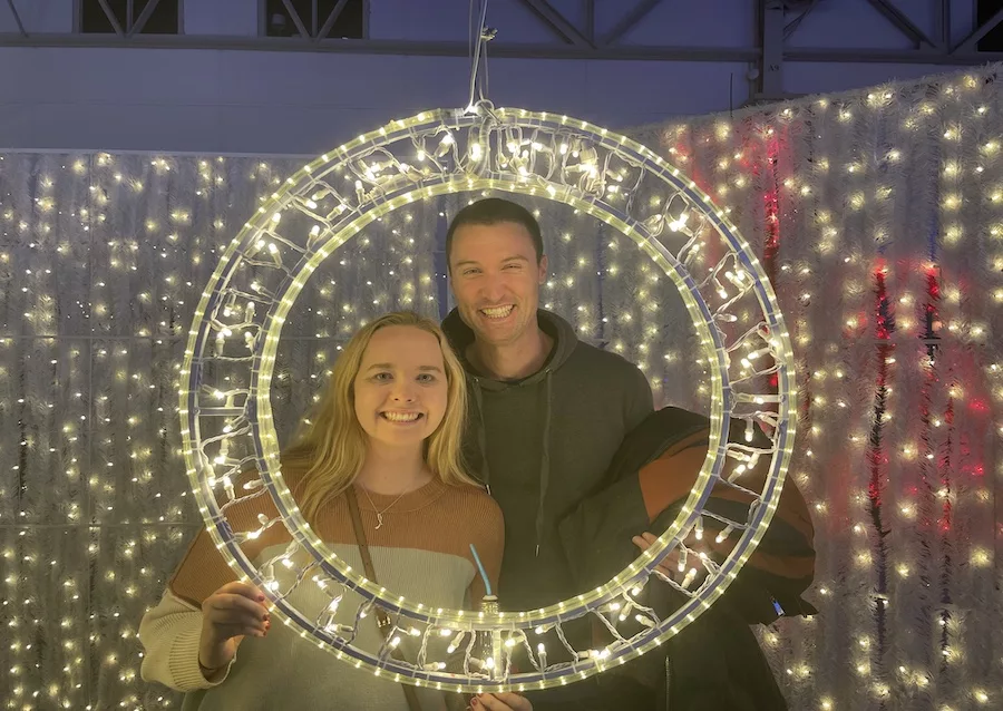 Couple posing in a holiday light frame. 