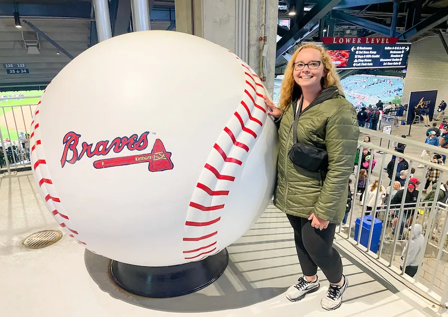 Young woman posing next to giant Braves baseball in Truist Park 