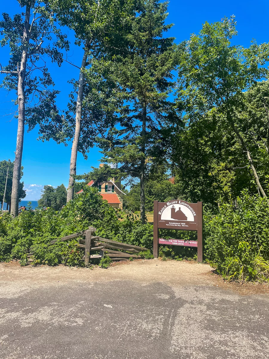Sign for Eagle Bluff Lighthouse surrounded by trees 