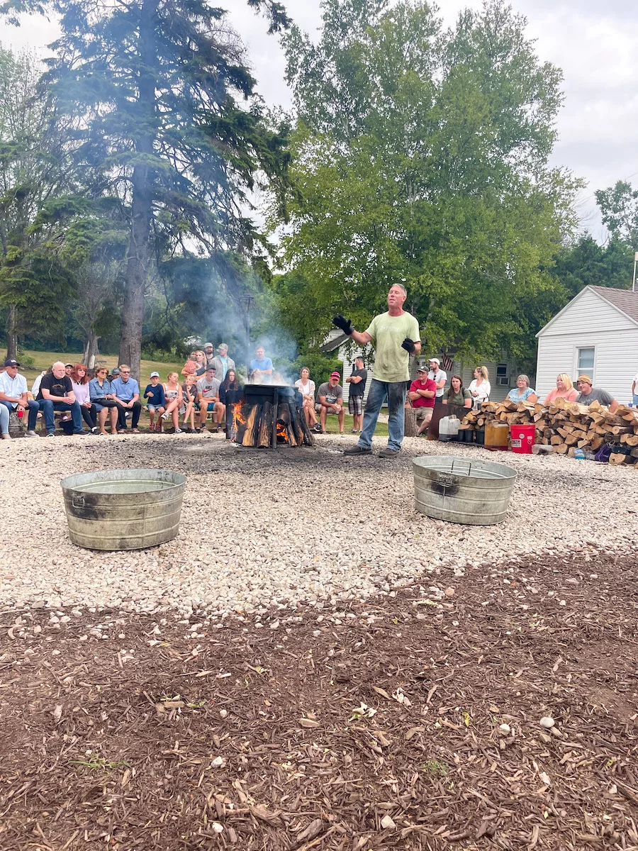People sitting around a fish boil in Door County with the fish boil master explaining the process. 