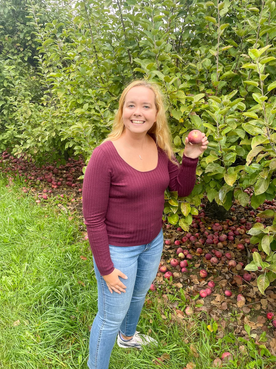 Woman posing with a freshly picked apple in an apple orchard 