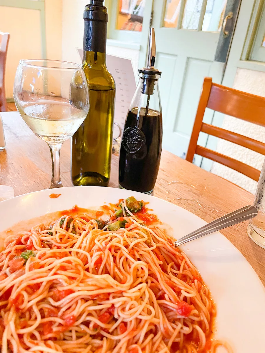 Restaurants in Springfield - large plate of spaghetti surrounded by a glass of wine and oils. 