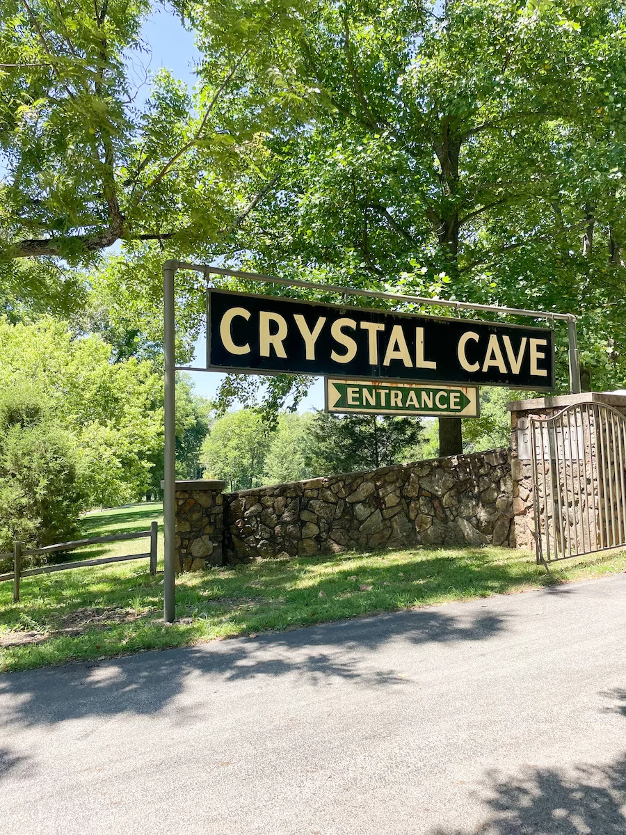 Caves in Missouri - Entrance sign to Crystal Cave, surrounded by green foliage, in Springfield, MO. 