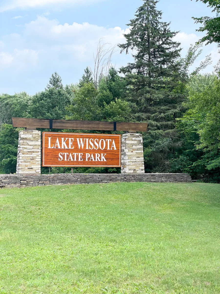 Outdoor activities in Eau Claire - Entrance sign to Lake Wissota State Park surrounded by green grass and trees 