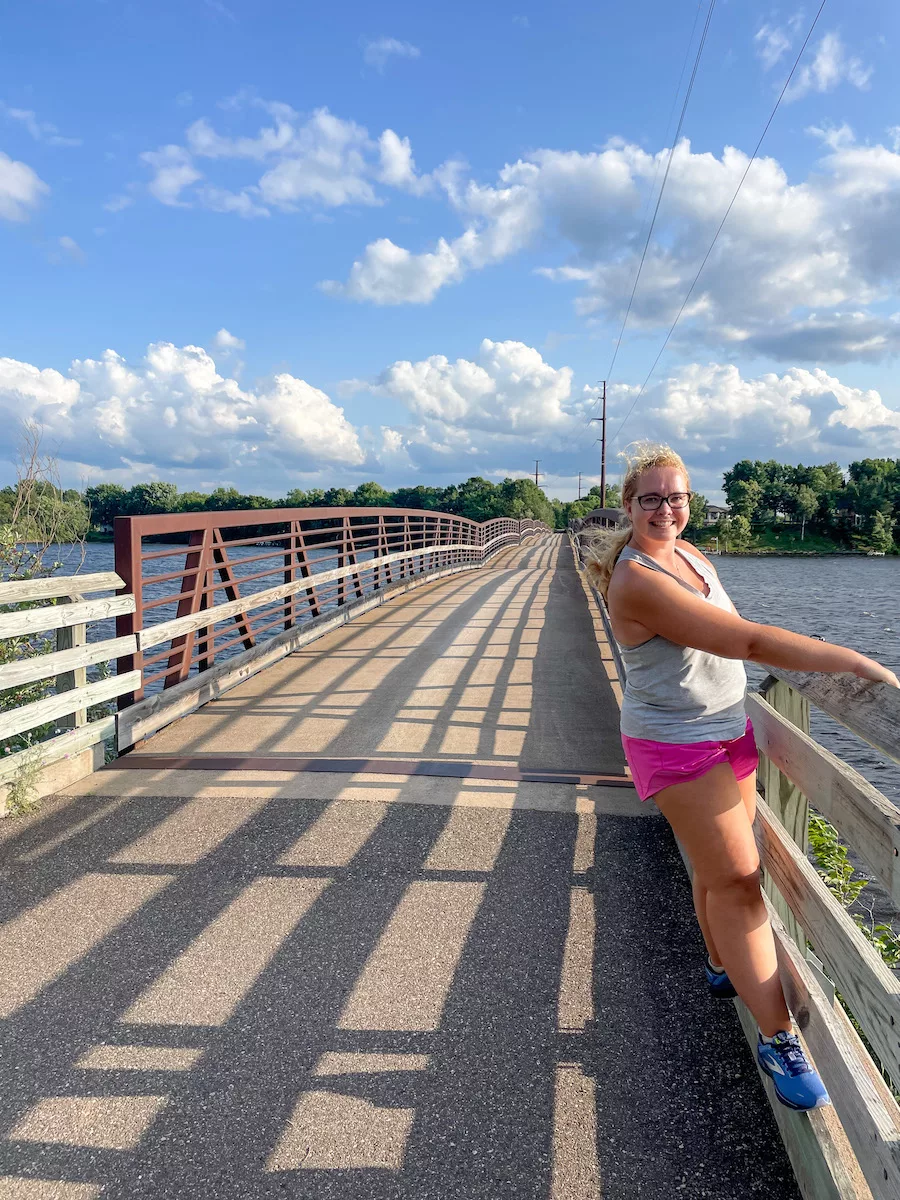 Woman on bridge that is part of Old Abe State Trail in Eau Claire, WI. Cloudy sky in background. 