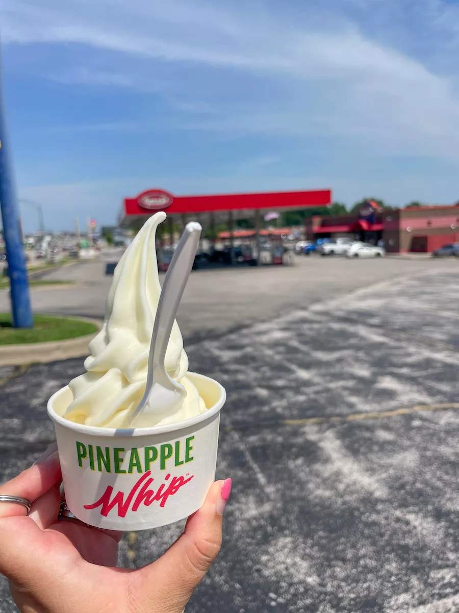 Pineapple Whip in a dish with a spoon featuring a blurred out background. 