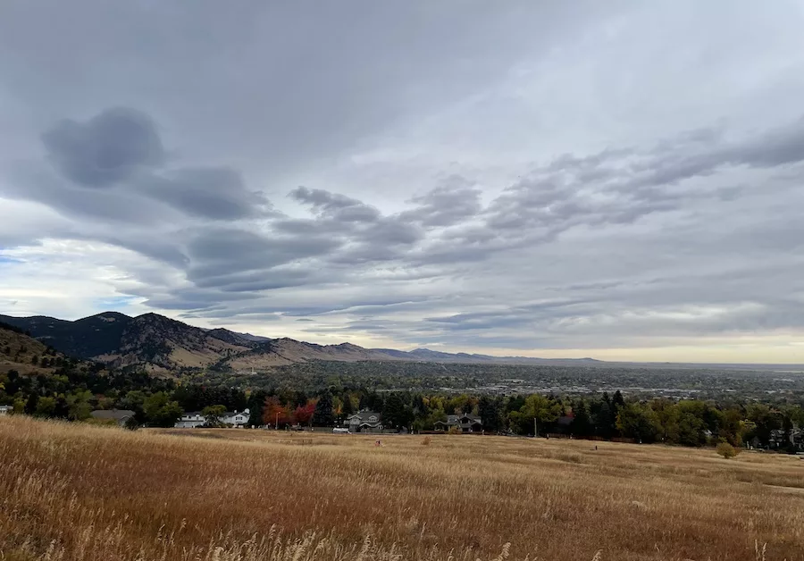 Overview of mountains and Boulder, CO community with a cloudy sky and yellow grass 