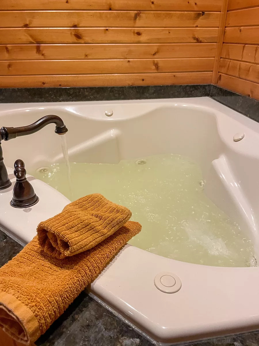 Half-full jetted whirlpool tub that is filling up at Hickory Hideaway Cabins 