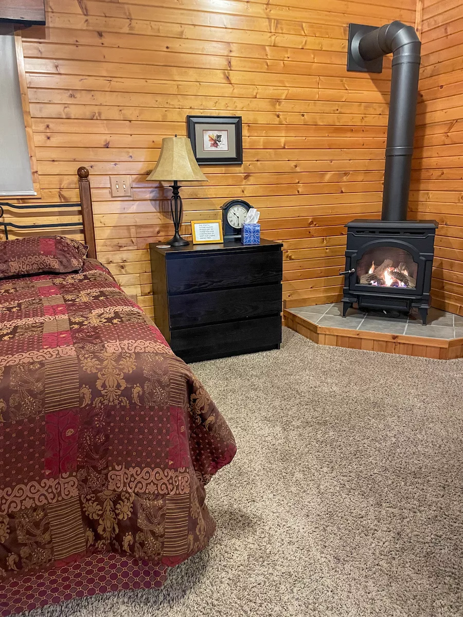 Bed, nightstand and fireplace in a wooden cottage 