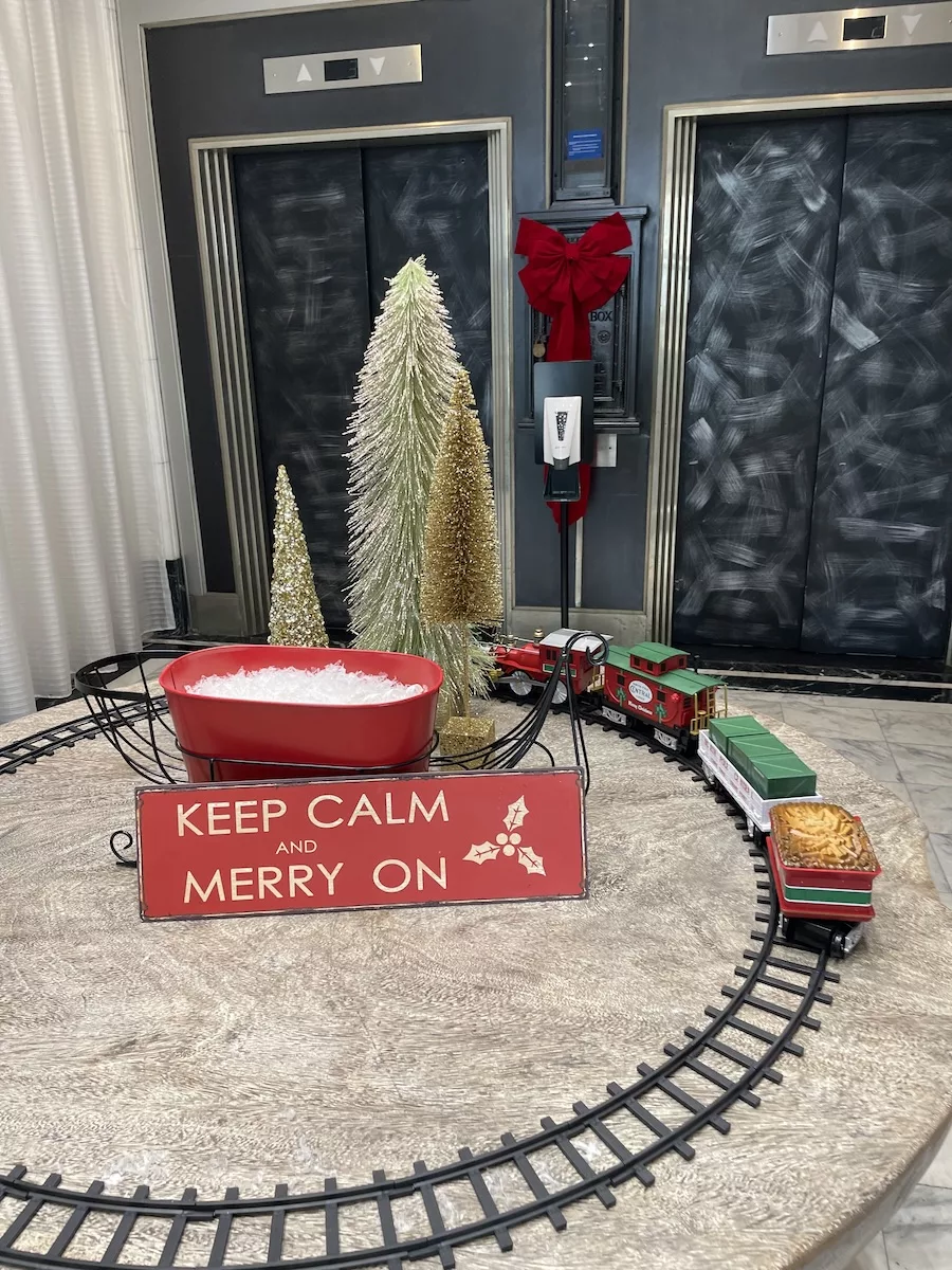 Keep Calm and Merry On sign with Christmas Train going around sign and tracks 