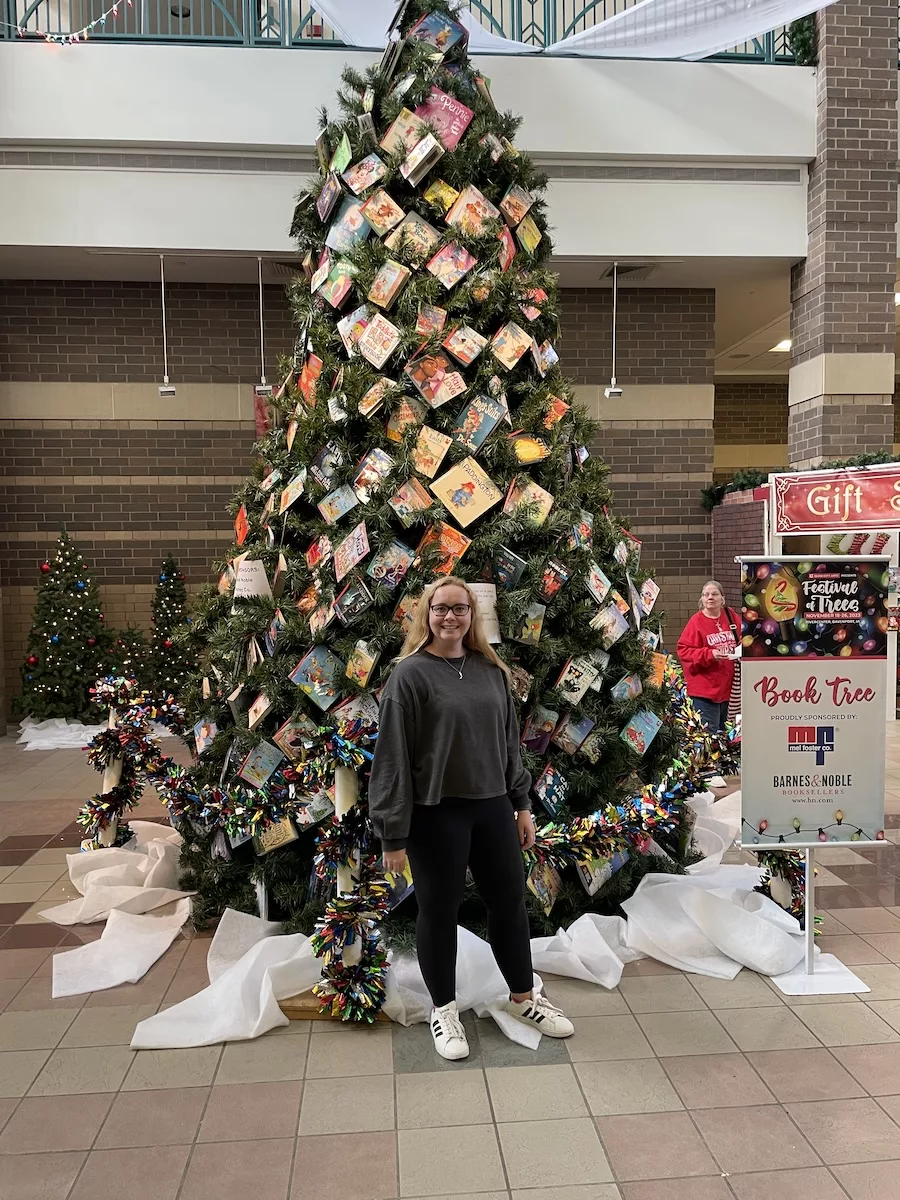 Woman in front of Christmas Tree decorated with books - Davenport, Iowa
