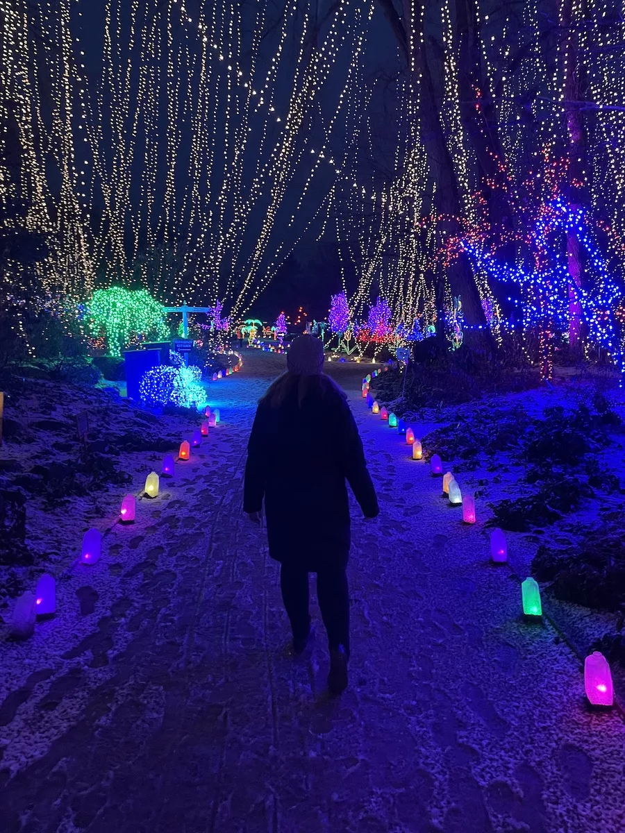 Young woman posing amongst bright holiday lights 