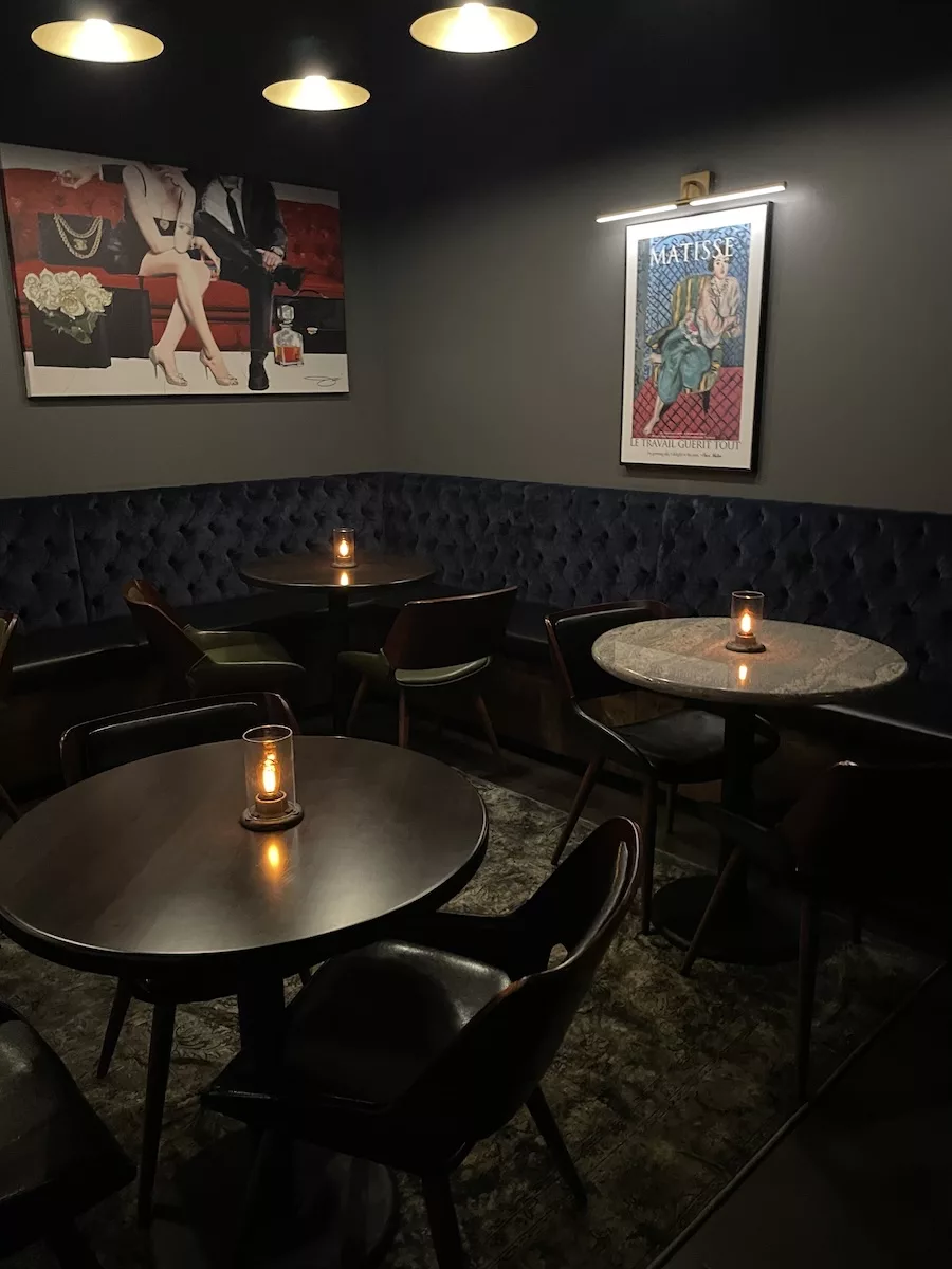 Image of three tables and chairs with candles in a dimly lit room - Garrison Speakeasy in Downtown Davenport
