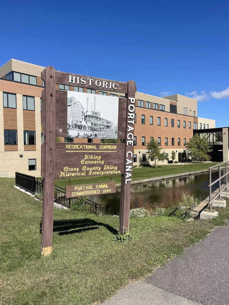 Image of Historic Portage Canal Sign with building and river in background - Portage Canal Segment 