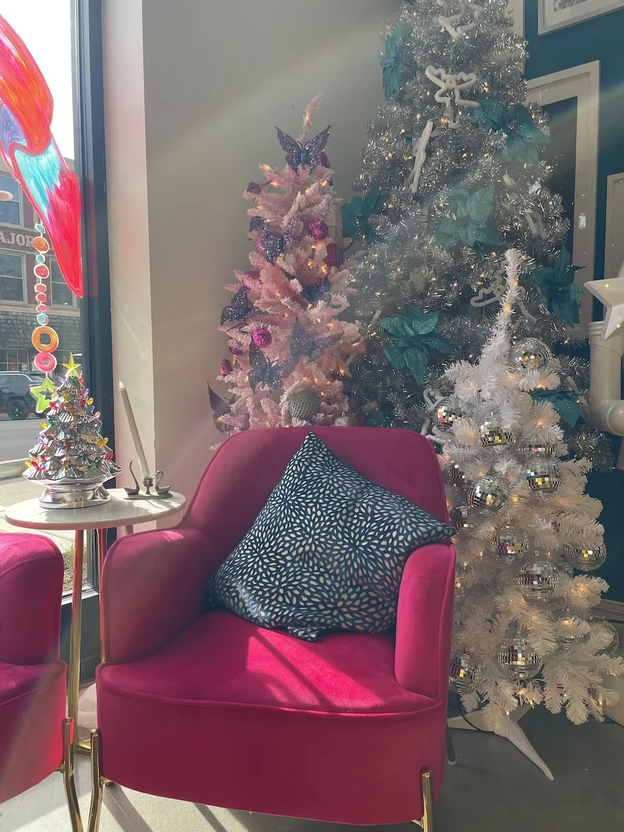 Pink arm chair surrounded by decorated Christmas trees in Tiphanie's 