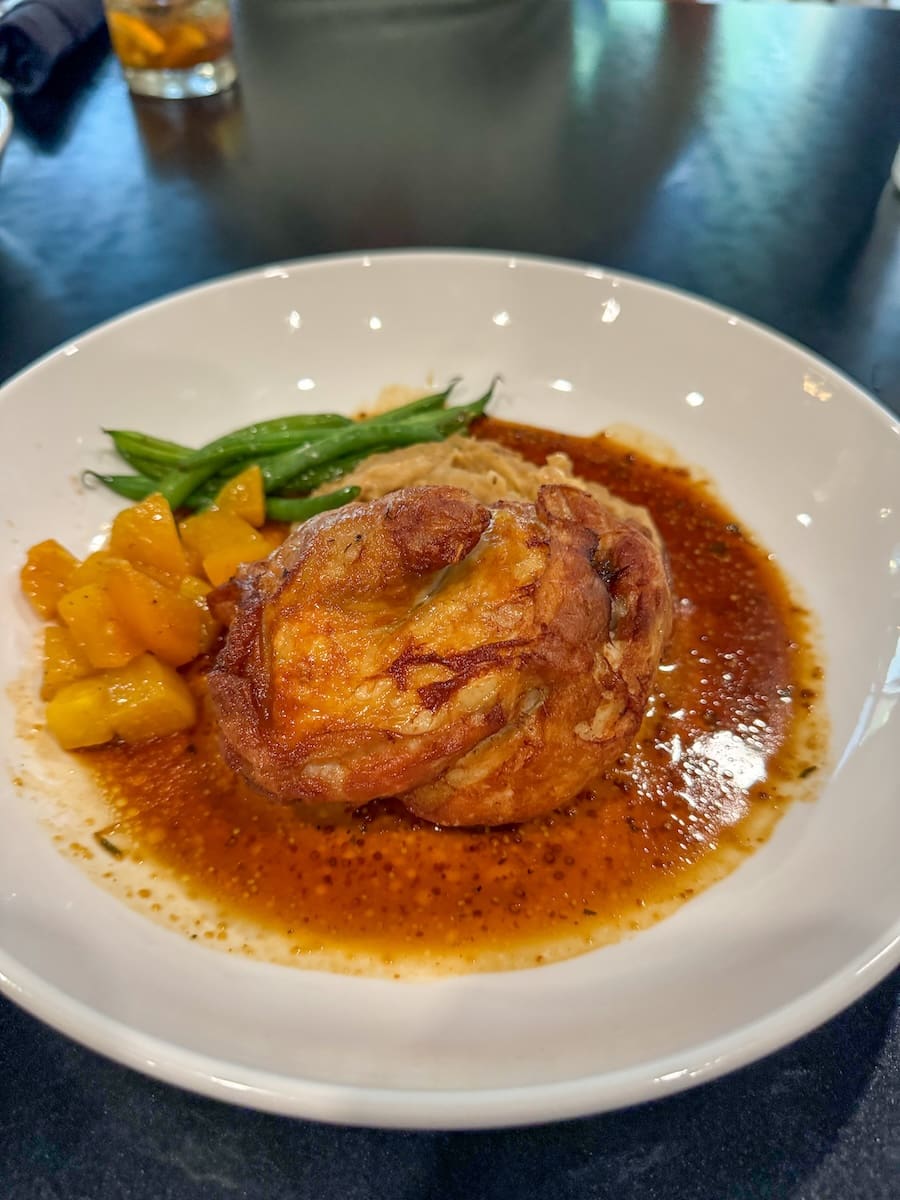 Image of chicken and veggies beautifully plated in a white dish at Black Pig Restaurant in Sheboygan, WI