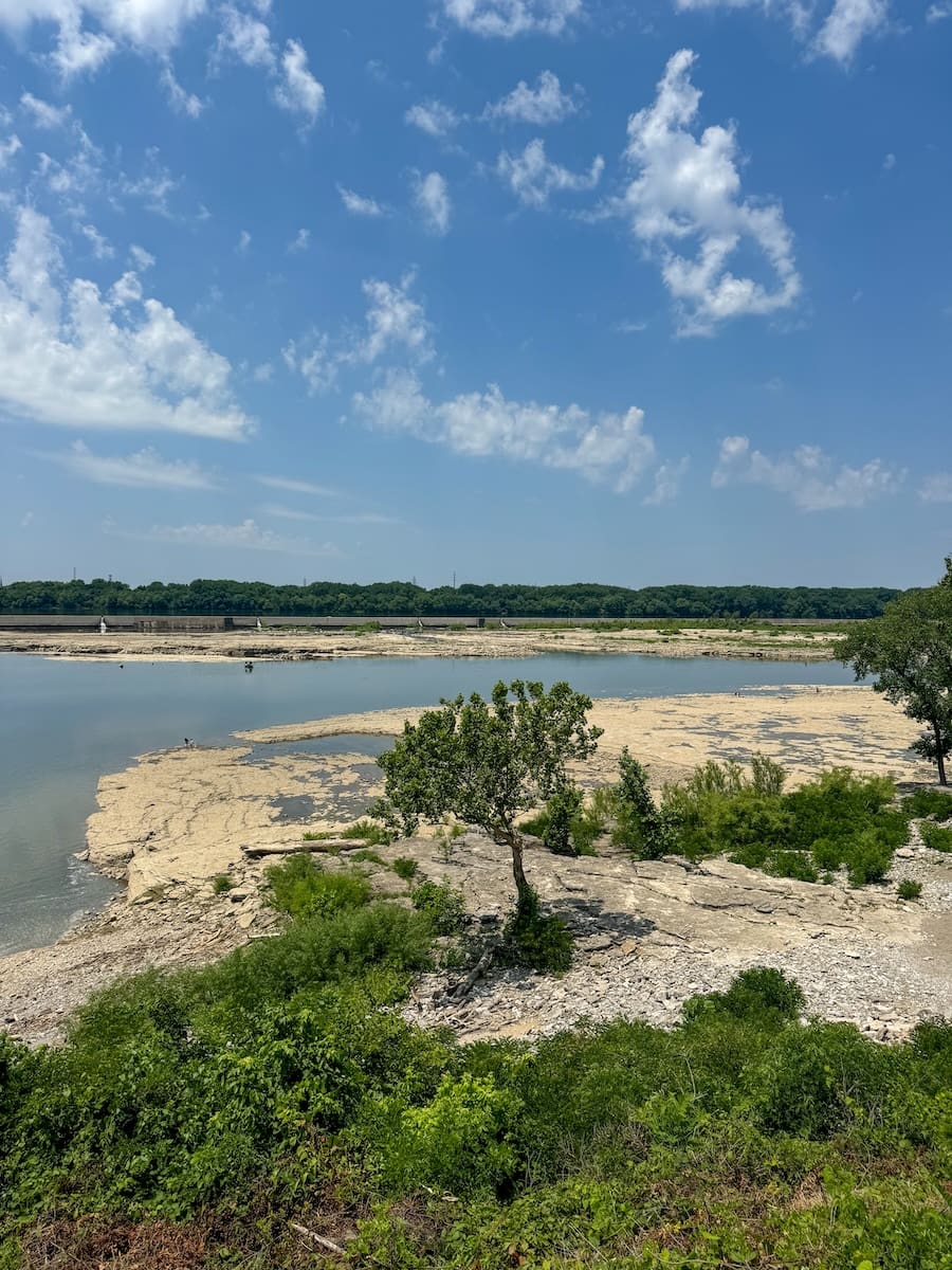 Image of Falls of the Ohio State Park with trees, rock formations and the Ohio River. 