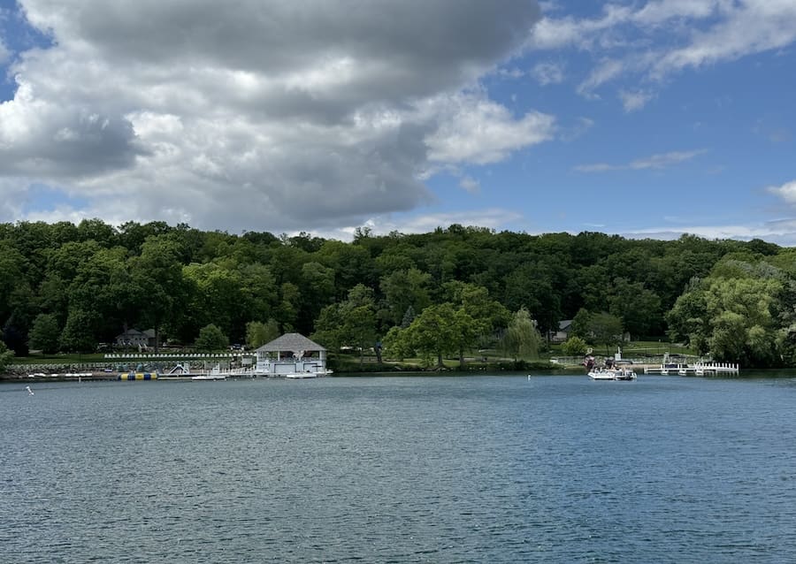 Image of mansions along Lake Geneva with a bright blue and cloudy sky. 