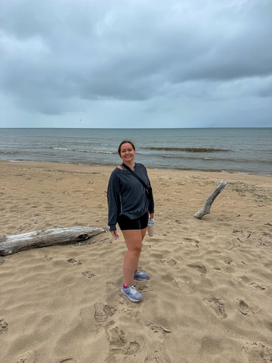 Image of young woman on sandy beach surrounded by cloudy sky and Lake Michigan in Sheboygan, Wisconsin. 