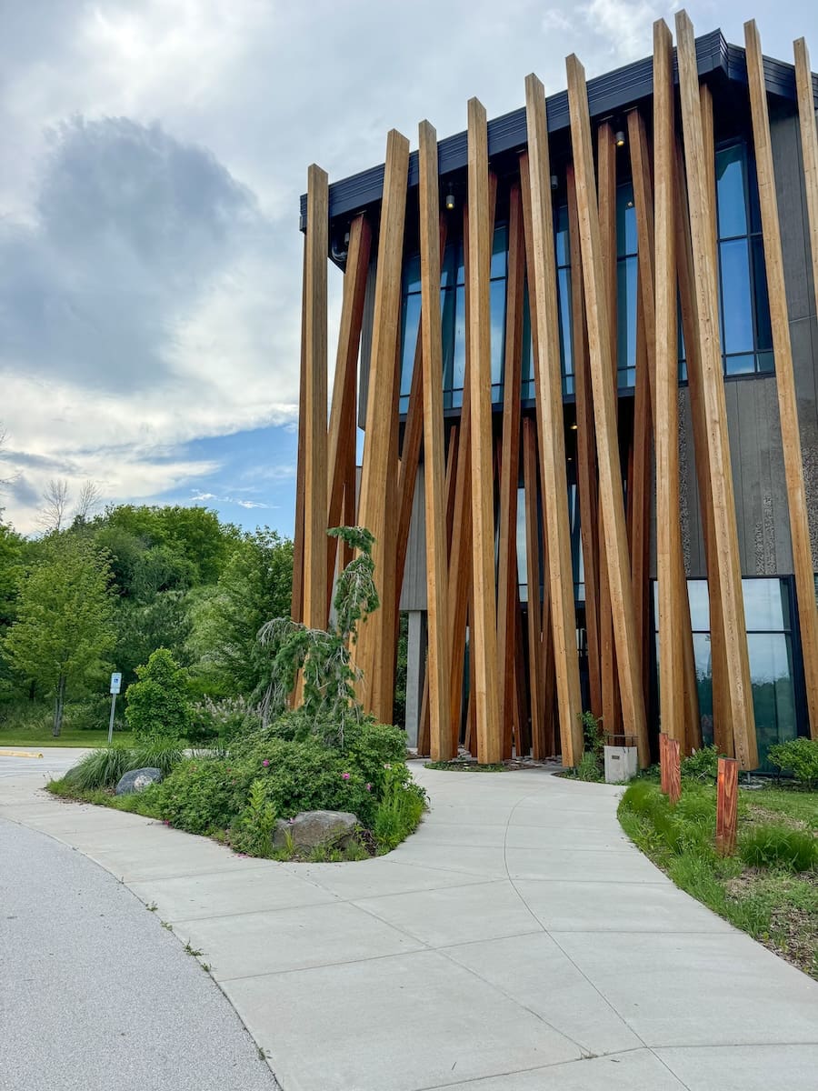 Image of art building with entrance covered by artful wood sticks. 