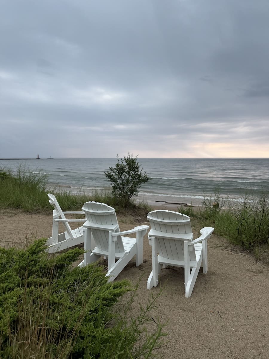 Image of 3 white chairs on the beach of Lake Michigan in Sheboygan, Wisconsin at Blue Harbor Resort