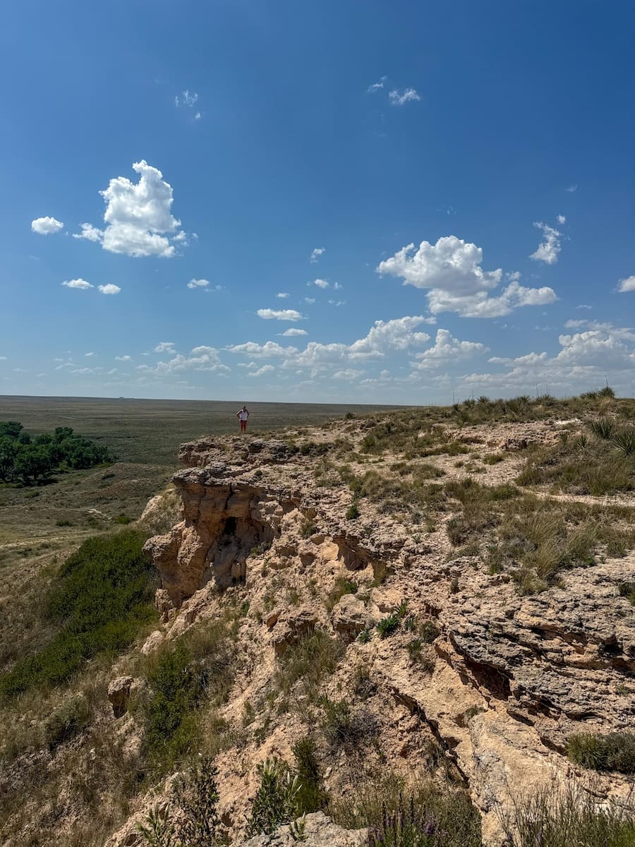 Image of a young woman standing at the edge of a rock in Cimarron National Grassland in Southwest Kansas