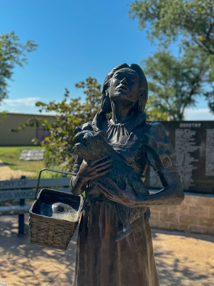 Image of a metal statue of Dorothy holding her dog Toto from the Wizard of Oz. 