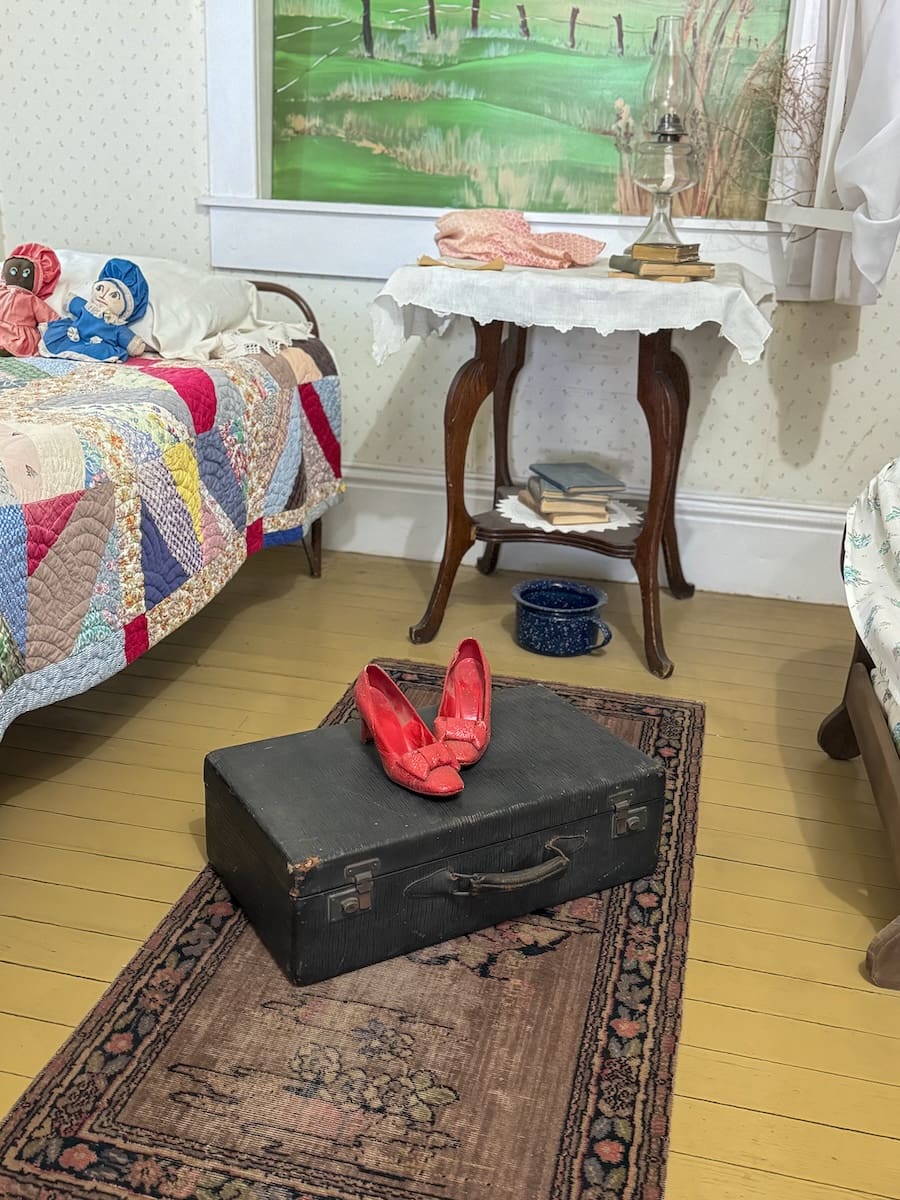 Image of a girls' bedroom with a suitcase on the floor and ruby red slippers on top of the suitcase - Liberal Kansas