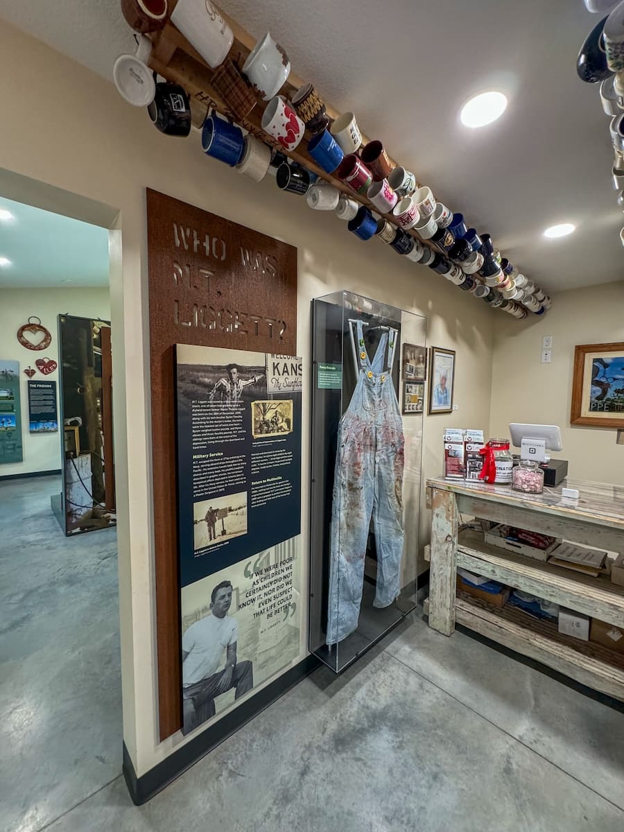 Image of a collection of mugs hanging from the ceiling and the entrance to a museum gallery. 