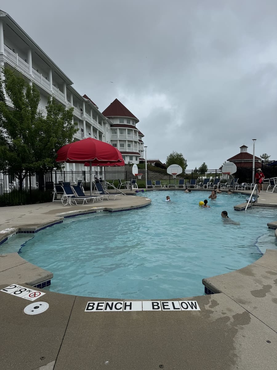 Image of a blue pool with kids splashing around, with a large resort in the background - Sheboygan, WI