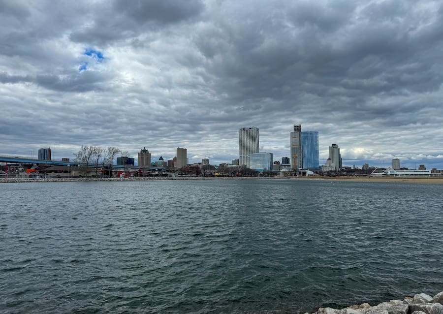 Image of downtown Milwaukee with a skyline in the background, Lake Michigan, and a dark cloudy sky. 