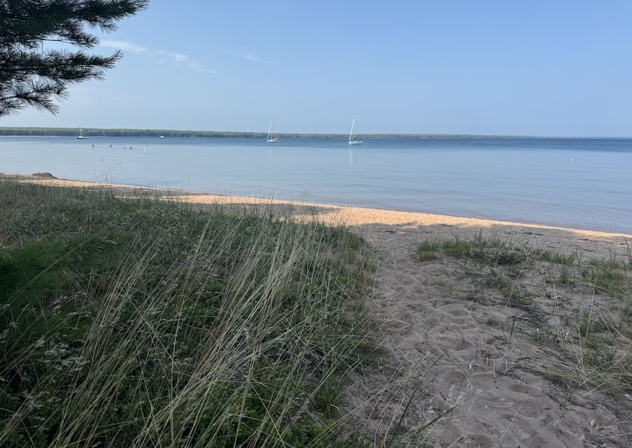 Image of sandy path leading to beach with Lake Superior and clear blue sky in the background.