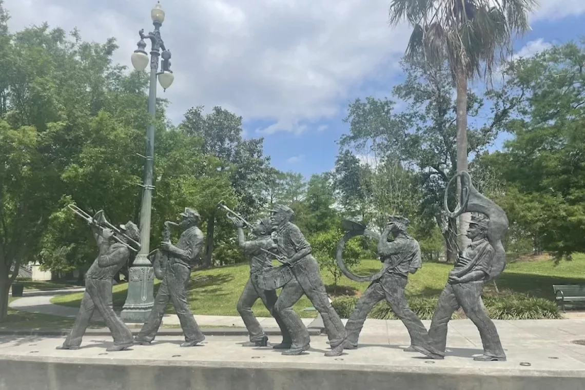 Image of metal musician sculptures in Louis Armstrong Park surrounded by green foliage - Honest Review of New Orleans