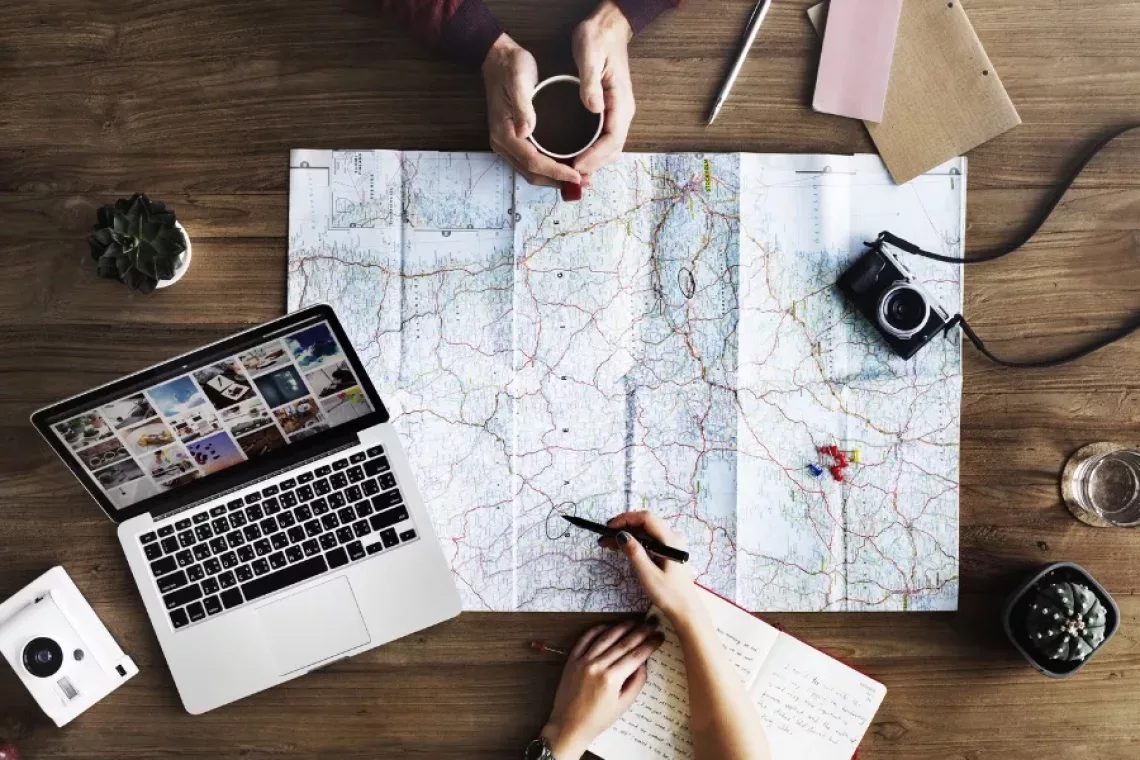 Photo of people planning out a trip with a map - Travel Resources cover photo (stock photo from canva.com by @agero-agnis).