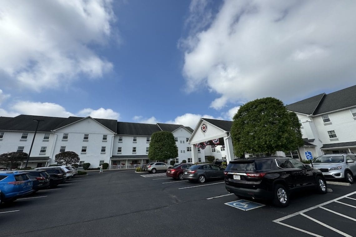 Image of a cloudy blue sky looming over a large white inn - Blue Gate Garden Inn Shipshewana Indiana