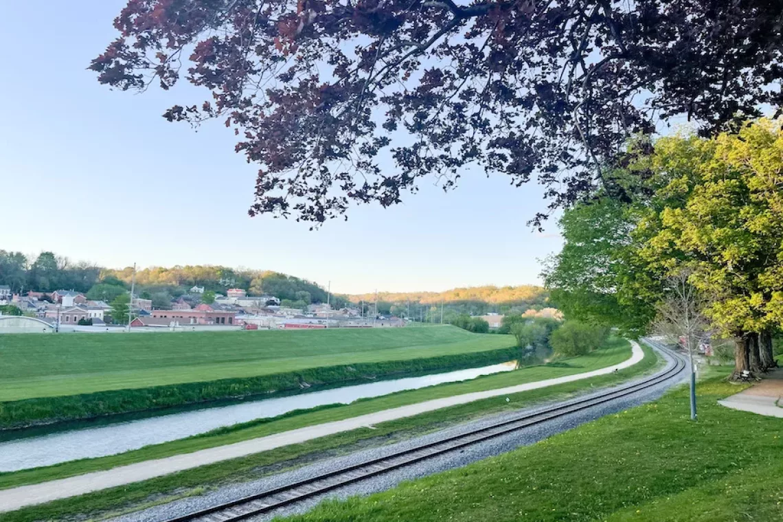 Things to do in Galena - View of river and trail surrounded by trees and grass. Downtown Galena in the distance.